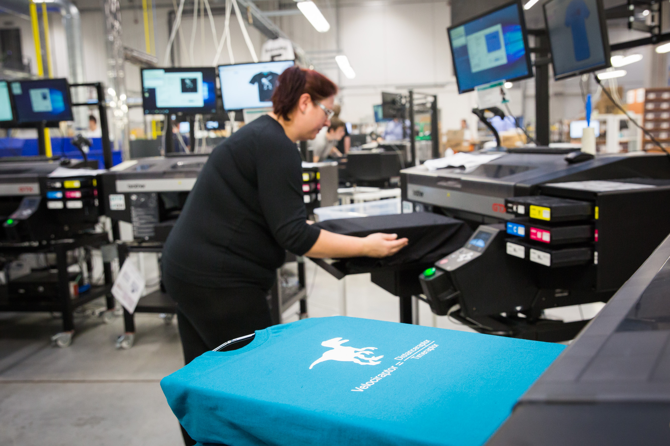 photo d'une femme qui utilise une imprimante pour imprimer un logo sur des t shirts